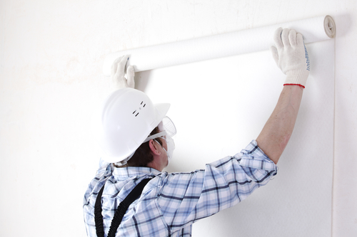worker attaching wallpaper to wall